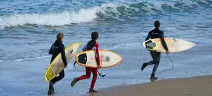 Groupe d'amis qui court sur le bord de mer pour faire du surf